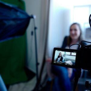 Woman being recorded in a professional studio setup, using video camera and lighting equipment.