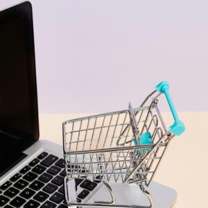 Mini shopping cart on a laptop symbolizes online shopping and e-commerce themes.